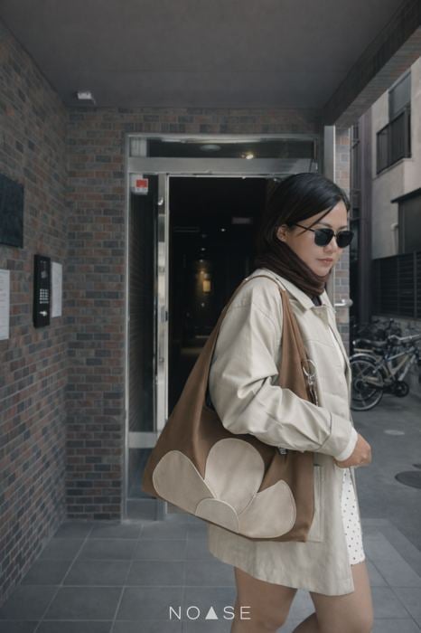 Woman wearing No Se sunglasses walking with a tote bag