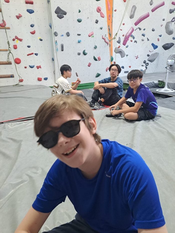 Teens wearing No Se sunglasses at an indoor climbing gym