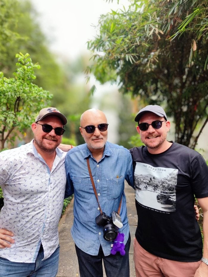Three men wearing No Se sunglasses on a garden path